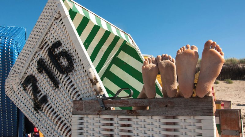 Bild på två par sandiga fötter som sticker upp ur en strandhytt i Tyskland.