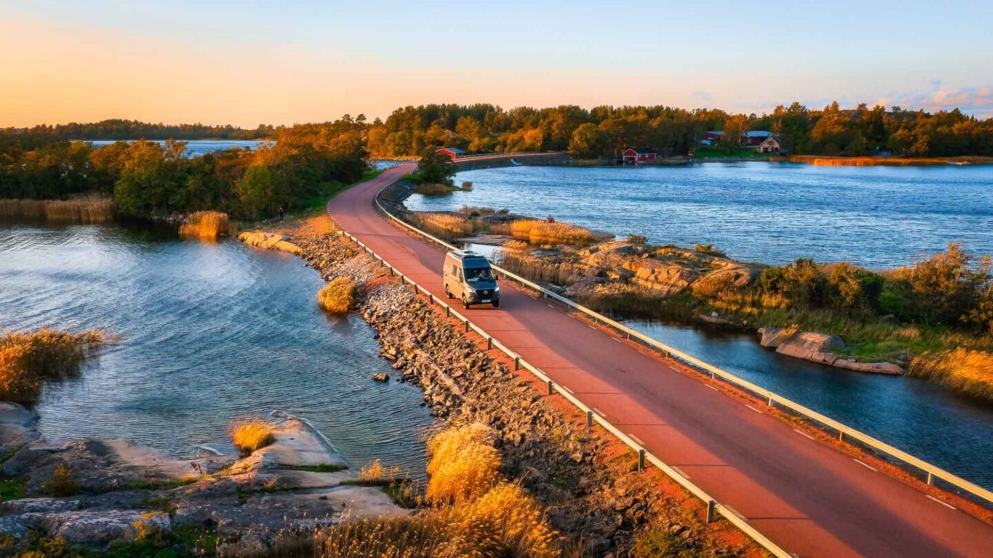Bild på en husbil som kör på en idyllisk väg genom finska skärgården