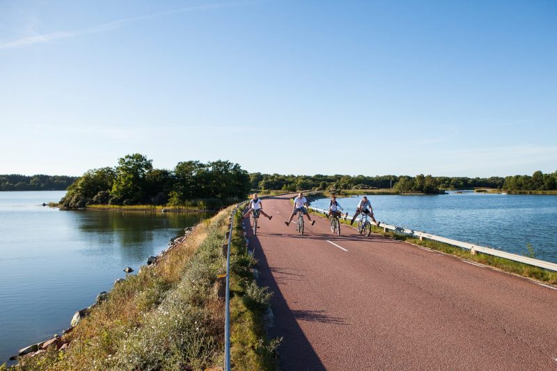 Bild på en glad familj som cyklar ute i Ålands skärgård