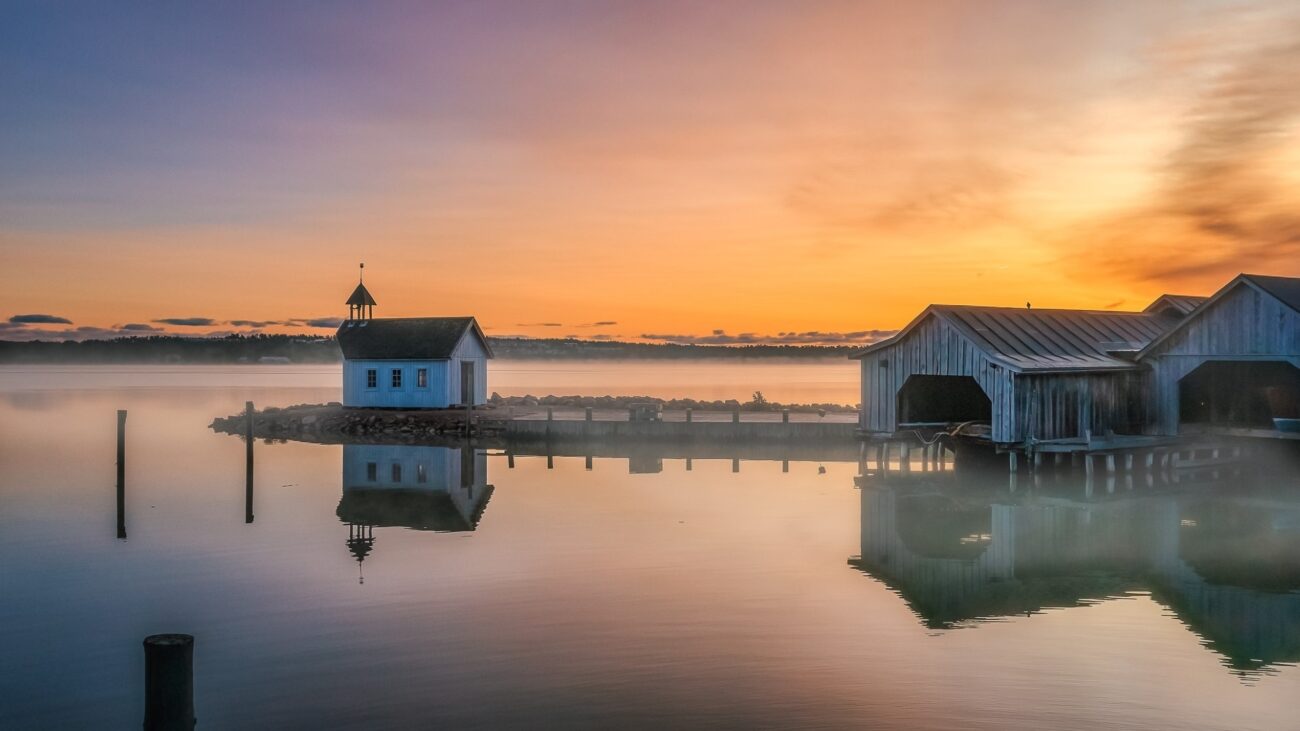 kleine Kapelle auf einer Landzunge im Wasser,daneben ein Schuppen und im Hintergrund der Sonnenuntergang