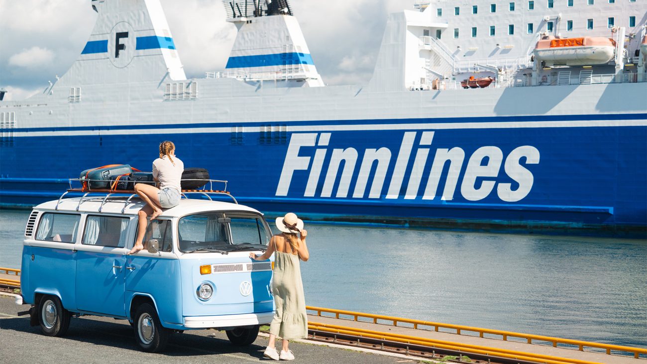 Frauen mit VW Bus vor blau-weißer Fähre auf den Weg nach Mikkeli. 