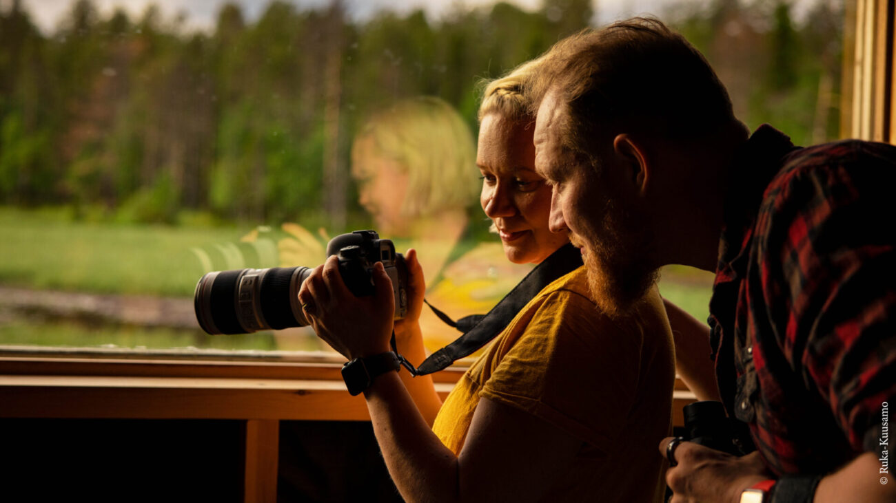 Mann und Frau schauen auf Fotokamera in Ruka-Kuusamo