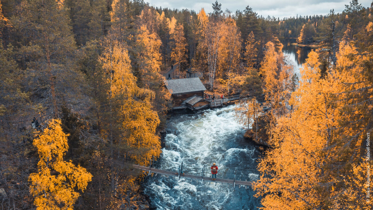 Fluss mit Brücke und Herbstbäumen in Ruka-Kuusamo
