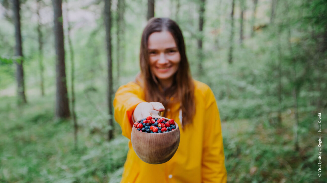 Frau mit Erd- und Blaubeeren im Wald von Jyväksylä.