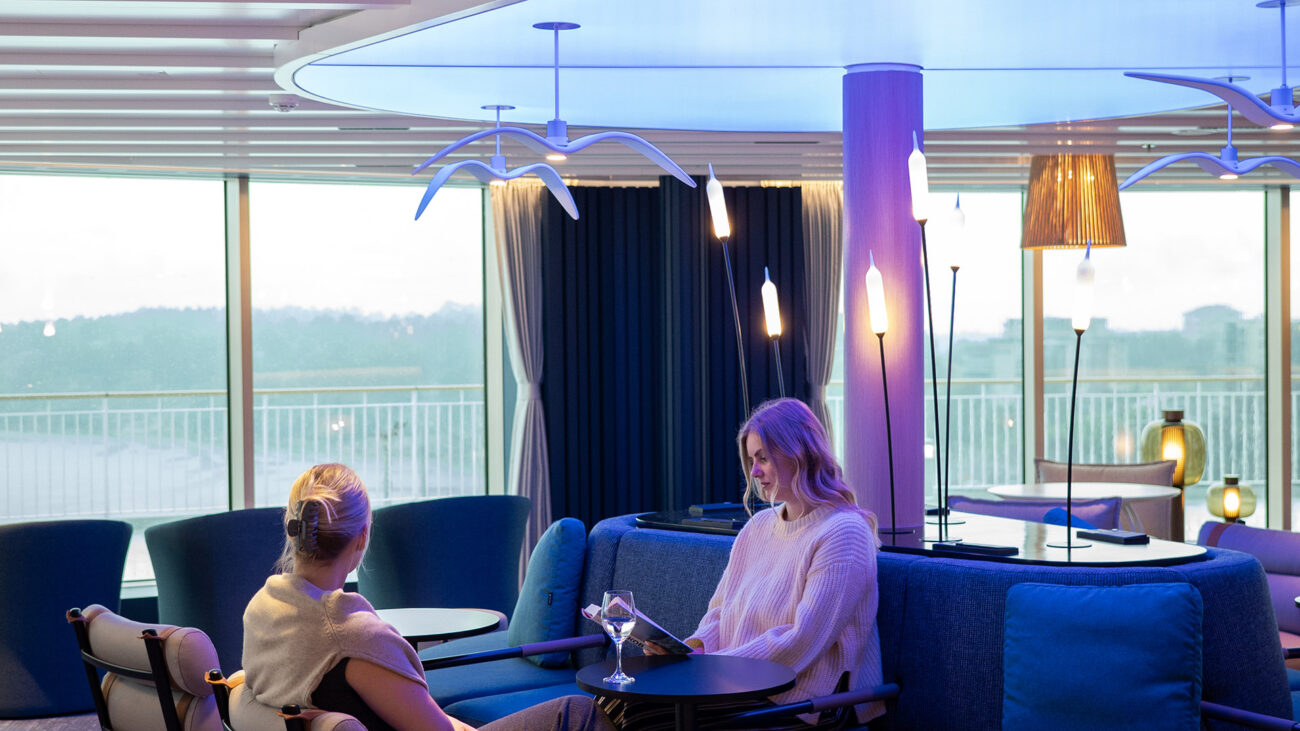 Premium Stellar Lounge on tila, joka tarjoaa rauhallisen miljöön merimatkalle. Avara lounge-tila sijaitsee uusien laivojen ylimmän kannen keulassa. Kuvassa kaksi naista juttelee loungessa.