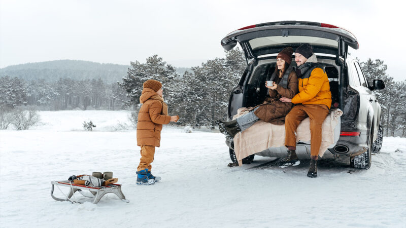 Mann und Frau mit Kind im Auto im Schnee
