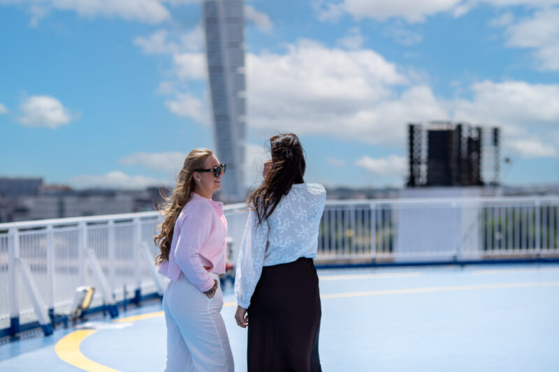 Bild på två tjejer ombord på Finnlines färja, med Malmö och turning torso i bakgrunden.