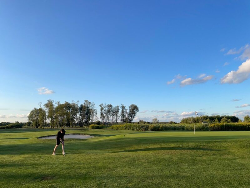 Bild på en golfare som ska chippa upp bollen på green.