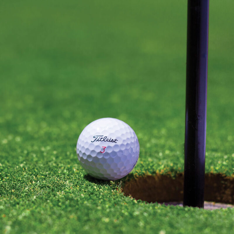 Bild på en golfboll som ligger precis innan hål på green.