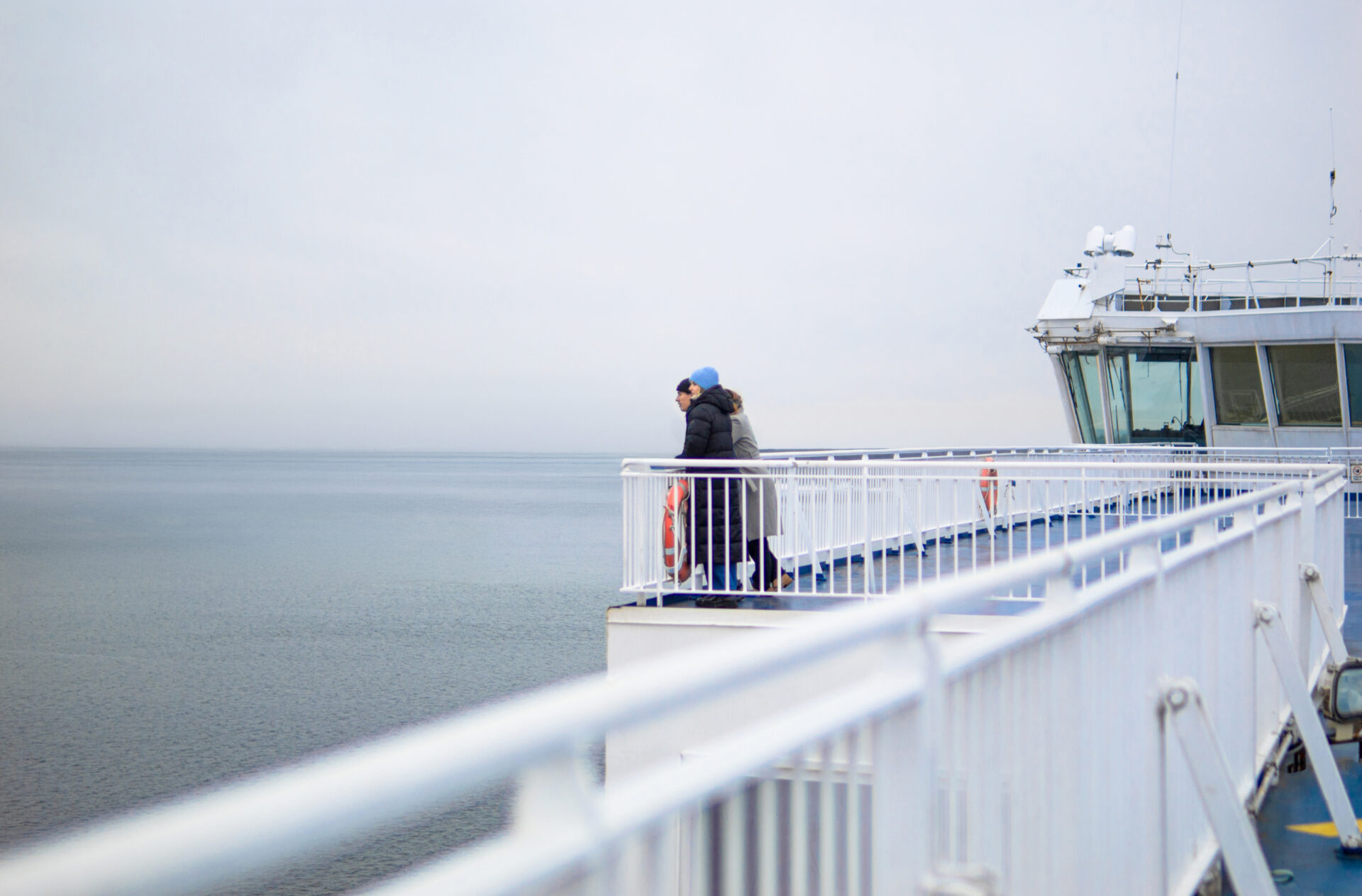 Bild på ett par som står vid relingen på däck ute till havs, ombord på Finnlines fartyg. 